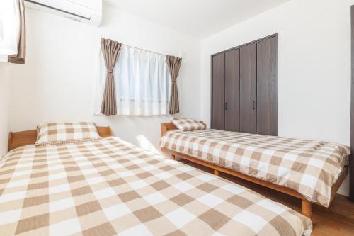 a bedroom with two beds and a window at 湘南楽軒 in Fujisawa