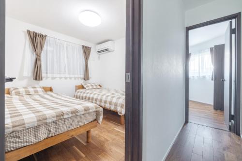 a bedroom with two beds and a sliding glass door at 湘南楽軒 in Fujisawa