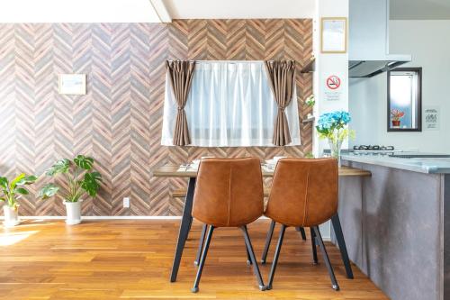 a kitchen with a table with two chairs and a window at 湘南楽軒 in Fujisawa