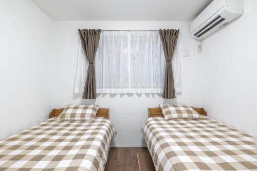 two beds in a room with a window at 湘南楽軒 in Fujisawa