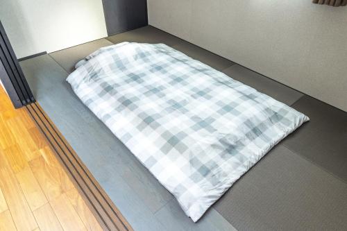 a plaid pillow sitting on the floor of a room at 湘南楽軒 in Fujisawa