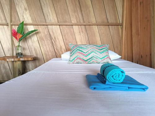 a bed with a blue towel on it with a pillow at Lodge El Amargal - Reserva Natural, Ecoturismo & Surf in Nuquí