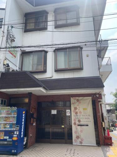 a tall white building with a store front at Guest House Kyoto Inn in Kyoto