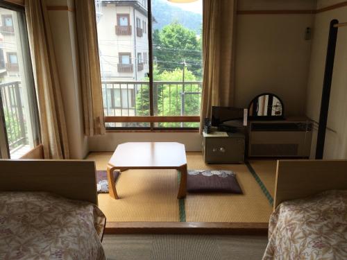 a bedroom with two beds and a table in front of a window at Uchihan in Nozawa Onsen