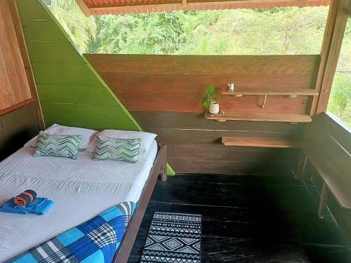 a small bed in a small room with a window at Lodge El Amargal - Reserva Natural, Ecoturismo & Surf in Nuquí