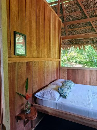 a bed in a wooden room with a window at Lodge El Amargal - Reserva Natural, Ecoturismo & Surf in Nuquí