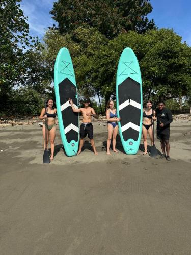 a group of people standing on the beach with surfboards at La posada in Nuquí