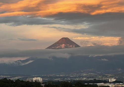a mountain in the sky with a layer of clouds at Airport and Volcano Views from 11th Floor Apartment in Guatemala