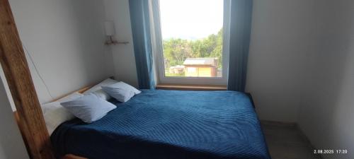 a small bedroom with a bed with a window at Na Górce 13 in Polańczyk