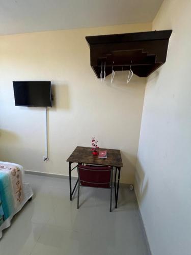 a small table in a room with a tv and a bed at Clora Hotel 