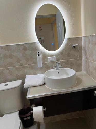 a bathroom with a sink and a toilet and a mirror at Clora Hotel 