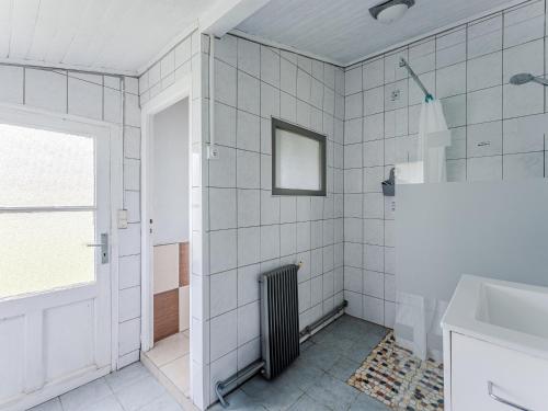un bagno piastrellato bianco con termosifone e finestra di Maison Landaise Spacieuse 6/7 Pers. à 500m du Lac - FR-1-521-252 a Sanguinet