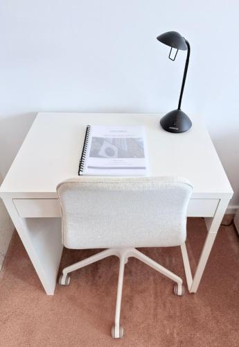 a white desk with a chair and a lamp at New High Floor Apartment in the heart of Canberra in Canberra