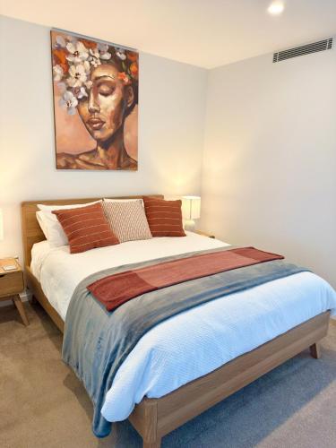 a bedroom with a large bed with a painting on the wall at New High Floor Apartment in the heart of Canberra in Canberra