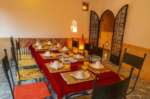 a dining room with a long table with red table cloth at Auberge La Fibule Du Dades in Aït Idaïr