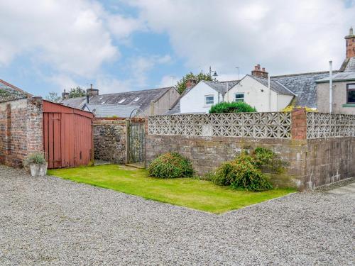 a brick fence with a yard with a red gate at The Moorings in Lochmaben