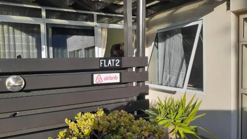 a sign on the side of a house with plants at Charming Room in Wellingtons Coastal Heart in Wellington