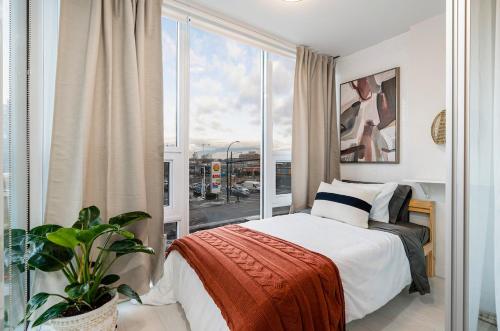a bedroom with a bed and a large window at Modern 4-Bed Condo with AC and Parking near SkyTrain for 6 in Vancouver