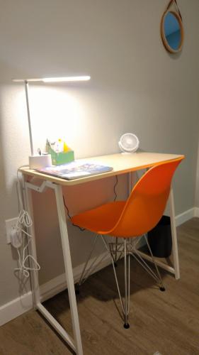 a desk with an orange chair and a lamp at Zen Den at Ciph Lab, Eco-Tech, Private Room, Direct BART Access to SF in Oakland