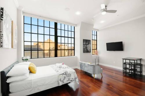 a white room with a bed and a television at XL Studio - Chic Flat - Rooftop Pool & Gym in Philadelphia