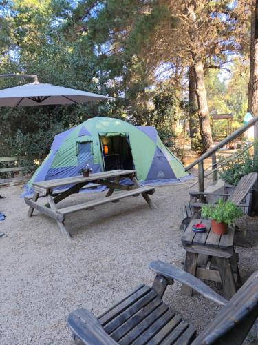 a tent and a picnic table with a bench and an umbrella at Glamping Puertecillo Surf & Camp in Puertecillo
