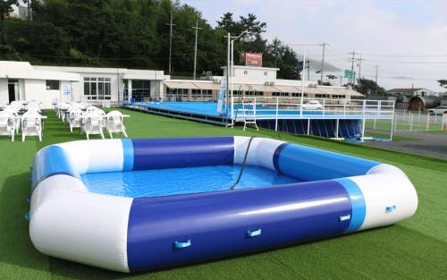 a large inflatable pool on a field with white chairs at Camp Village Geoje in Geoje 