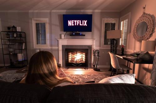 a woman sitting on a couch in a living room with a fireplace at Villa Signor in Norwich