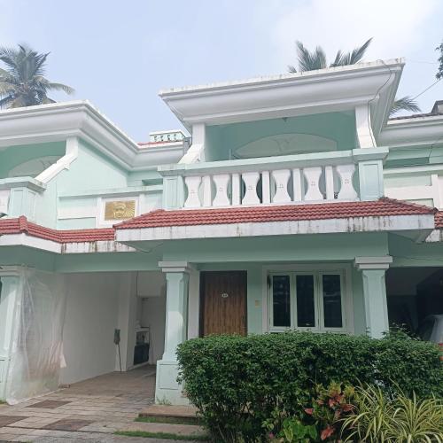 a white house with a balcony on top of it at Mint Villa in Benaulim