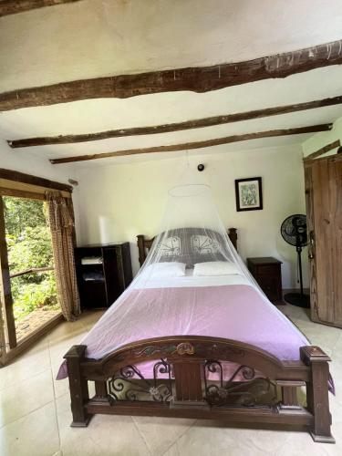 a bedroom with a bed with a purple blanket at cabaña tibiki, minca in Santa Marta