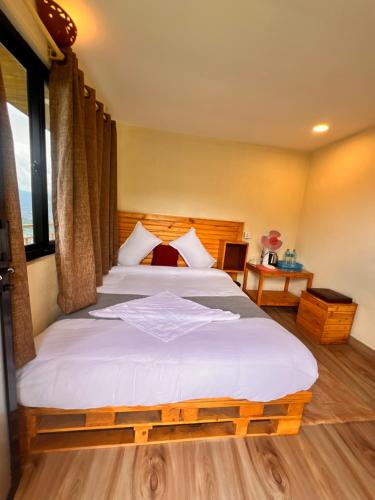 a bedroom with a large bed with white sheets at Mountain View cafe in Pokhara
