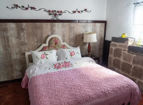 a bedroom with a pink bed with a wooden headboard at Hotel Boutique Casa de Hacienda Su Merced in Puembo