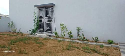 a white building with a black door and some plants at Om Villa in Mandvi