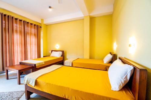 two beds in a room with yellow walls at Traveller's Villa in Hatton