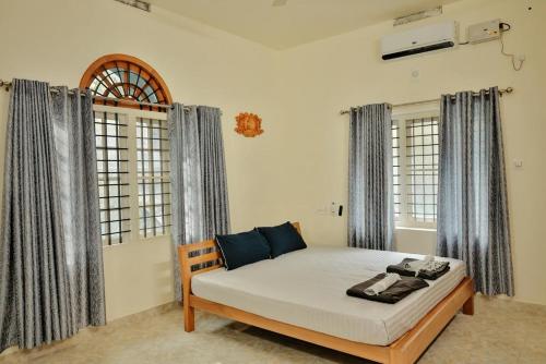 una camera da letto con un letto in una stanza con finestre di Nila Heavens - Spacious 5 BHK Homestay , ideal for families a Guruvayoor