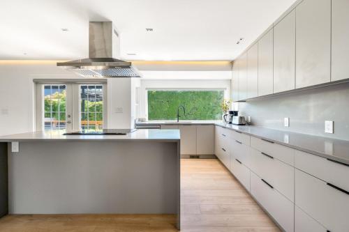 a large kitchen with white cabinets and a sink at Luxury&Brand-new 3BD 2BTH House in Burnaby