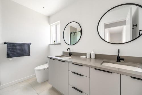 a white bathroom with a sink and a mirror at Luxury&Brand-new 3BD 2BTH House in Burnaby