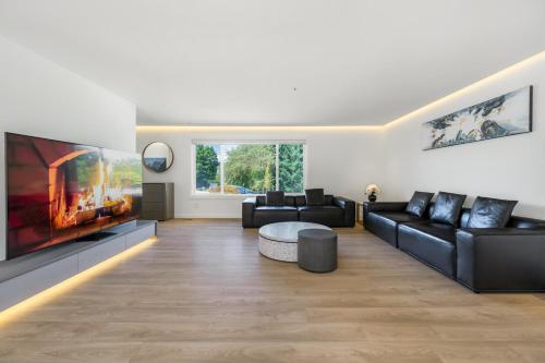 a living room with black furniture and a large tv at Luxury&Brand-new 3BD 2BTH House in Burnaby
