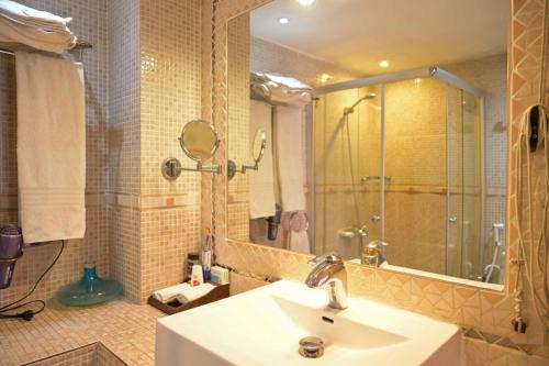 a bathroom with a sink and a shower with a mirror at Hotel Brajas in Antananarivo