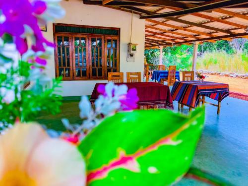a patio with tables and chairs and purple flowers at Sigiriya Luminary Homestay in Sigiriya
