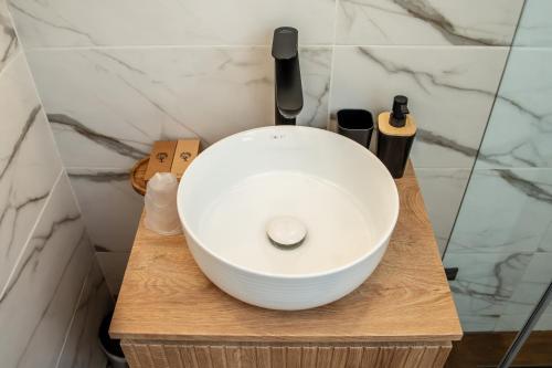 a white bowl sink on a wooden stand in a bathroom at Volotel SkyWay in Cluj-Napoca