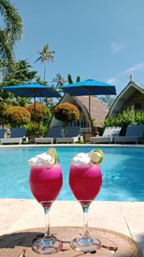 two cocktails sitting on a table next to a pool at Casa Azzurra in Gili Islands