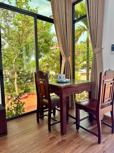 a dining room with a table and chairs and a window at The Mango Villas in Hoi An