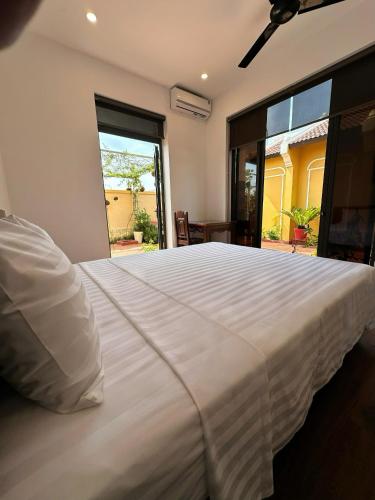 a large white bed in a bedroom with a large window at The Mango Villas in Hoi An