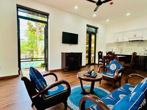 a living room with a couch and chairs and a television at The Mango Villas in Hoi An
