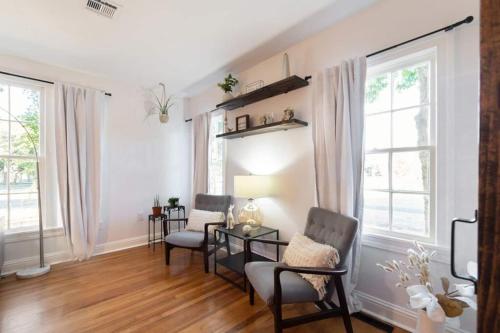 a living room with two chairs and a table and windows at Luxury Bungalow Near Main W Hot-tub And Firepit in Fredericksburg