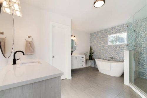 a white bathroom with a tub and a sink at Luxury Bungalow Near Main W Hot-tub And Firepit in Fredericksburg