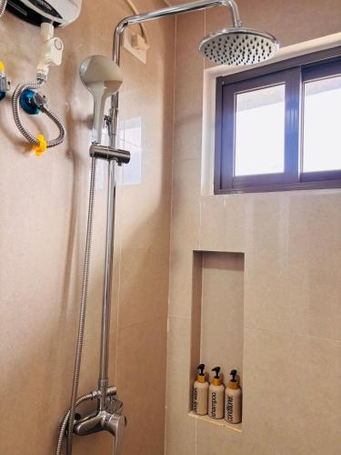 a shower in a bathroom with four bottles on the wall at WV 11 Light & Fresh Studio in Iloilo City
