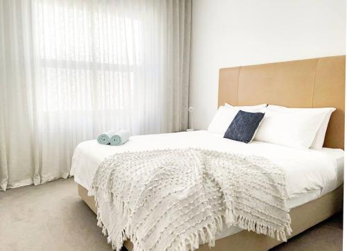 a bedroom with a white bed with a large window at Pearl on Pakenham- Modern & Central w king beds in Fremantle