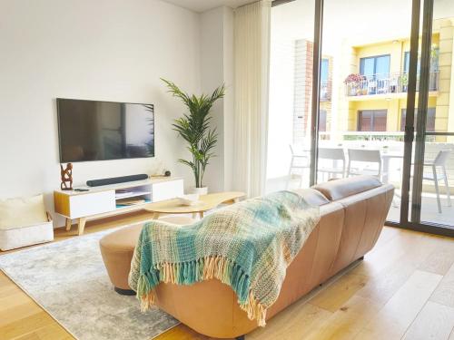 a living room with a couch and a flat screen tv at Pearl on Pakenham- Modern & Central w king beds in Fremantle