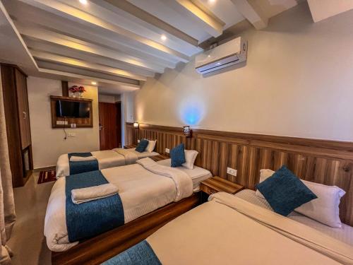 a hotel room with two beds and a tv at Novetel Boutique Home in Pokhara